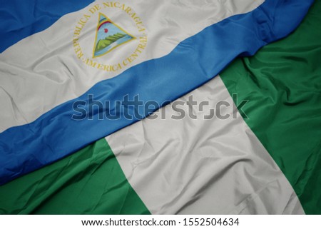 waving colorful flag of nigeria and national flag of nicaragua. macro