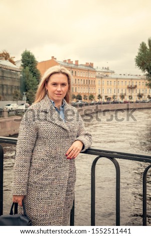 Portrait of a young woman walking along the canal in St. Petersburg in autumn on a Sunny day