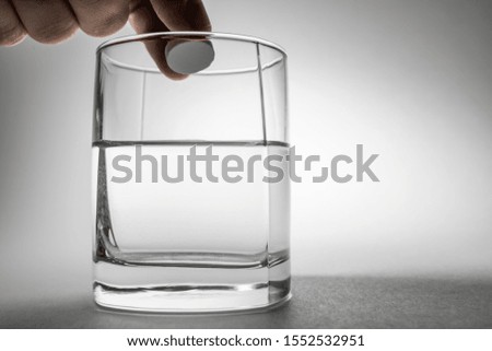 The effervescent tablet dissolves in a glass of water.