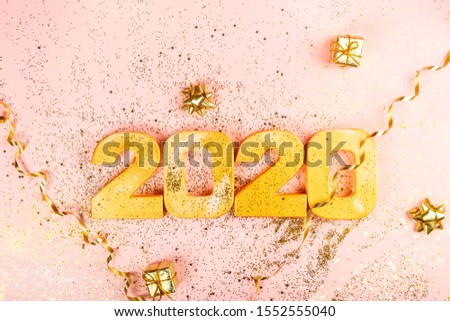 Happy New Year 2020. Digits 2020 are on pink background with glitter. Holiday Party Decoration or postcard concept with top view and copy space.