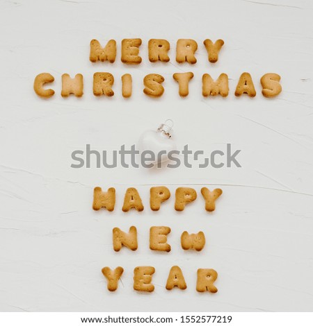The words merry christmas and happy new year are made of cookie letters. Flat lay composition for greeting card om white textured background.