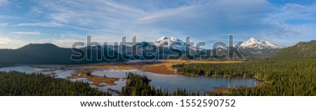 Aerial panorama view of picturesque northwest natural landscape with beautiful snowcapped mountains in distance past tranquil lake Royalty-Free Stock Photo #1552590752