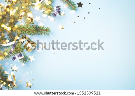 Blue Christmas background with fir branches, golden serpentine and confetti with copy space for text. New Year greeting card.