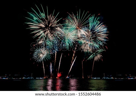 Amazing beautiful colorful fireworks display on celebration night, showing on the sea beach with multi color of reflection on water