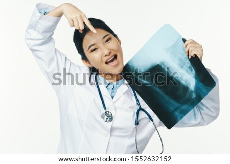 female doctor in a medical coat shows a finger at an x-ray