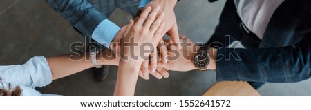 panoramic shot of businesswoman and businessmen putting hands together 