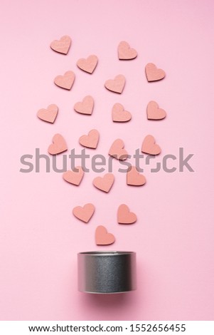 Silver metal gift box and decorative wooden hearts on pink background. Holiday concept. Top view