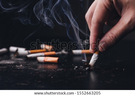 Close up hand held a cigarette to crush smoke of a burning, Stop smoking concept.World No Tobacco Day