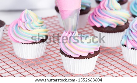 Step by step. Frosting unicorn chocolate cupcakes with rainbow color buttercream frosting.