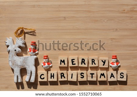 Merry Christmas in 3D wooden alphabet letters with Santa snowmen and a wood reindeer decoration on a bamboo background with copy space