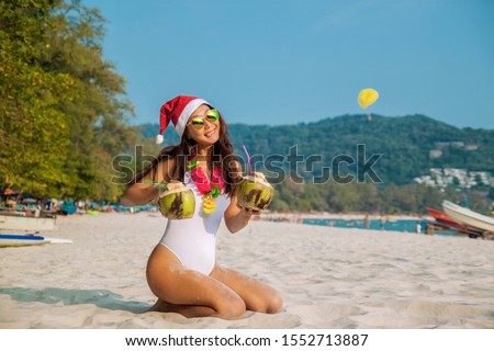 Christmas Santa hat bikini woman on beach holidays travel vacation getaway. Beautiful girl in bikini having fun in the sun.