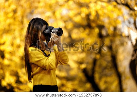 woman photographer with professional camera takes pictures in nature in autumn, copy space