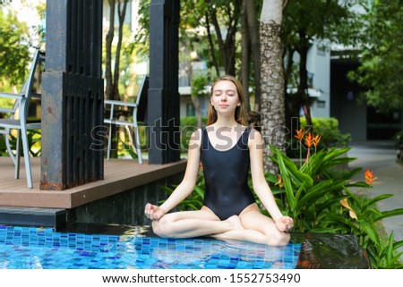 fitness healthy woman sit in lotus position doing yoga by swimming pool on sunny day. concept of physical or mental action, supreme being or receive good karma