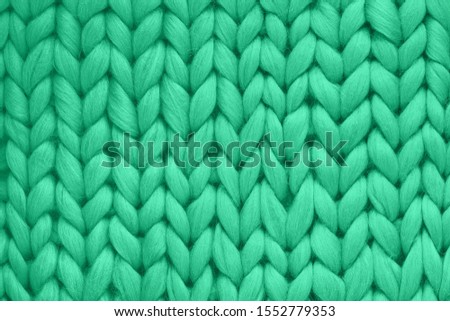 Texture of green wool big knit blanket. Large knitting. Plaid merino. Top view