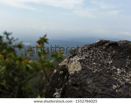 macro picture of stone with landscape of blurred sky and white clouds at mountain top 