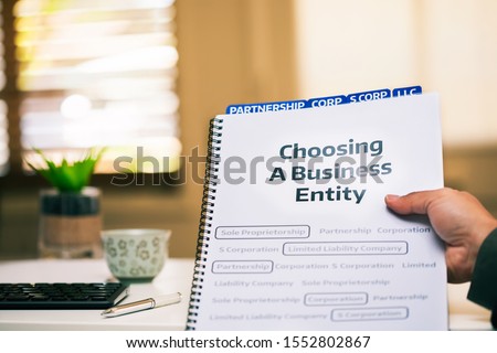 A document on different types of business formations being read by a small business owner while sitting in office desk. Royalty-Free Stock Photo #1552802867