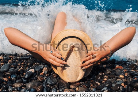 A girl is lying on a beach of pebbles. Splashing waves
