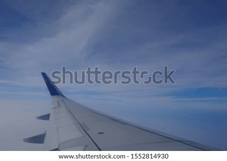 the wings of an airplane fly between clear blue skies and white clouds of cotton. the aircraft flew above an altitude of 20,000 feet.