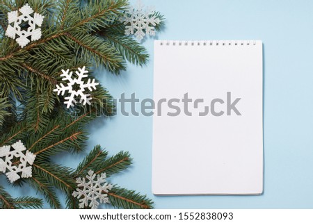 Note book with Wish List. Snowy fir branches on blue background, copy space. Christmas and winter concept.