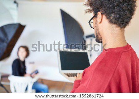 Young photographer at the laptop computer is preparing a photo shoot