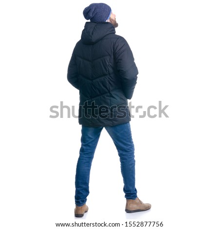 Man in winter jacket and warm hat standing looking on white background isolation, rear view