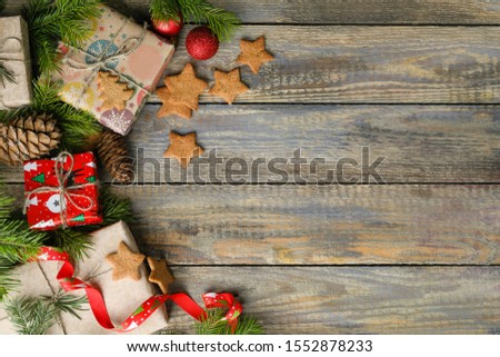 horizontal photo with christmas presents, pine nuts, cones, on wooden background with christmas tree and place for text on the right .
