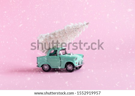 Christmas decoratoin . On a pink toy car with christmass tree on it . With snow texture .