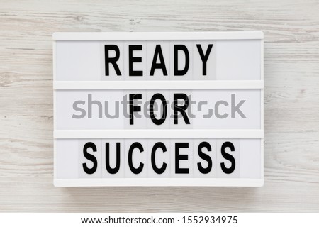 'Ready for success' words on a modern board on a white wooden background. Overhead, from above, flat lay. 