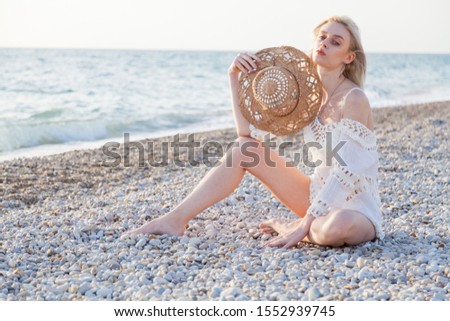Portrait of a beautiful fashionable woman on the beach by the ocean