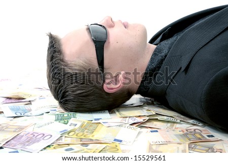 Young man wearing sunglasses laying on large amount of money