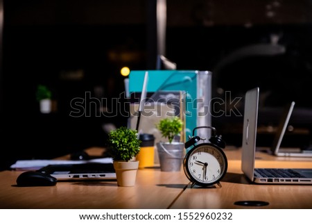 Desk table at night with analog clock , in Overtime work or work late night office concept with copy space