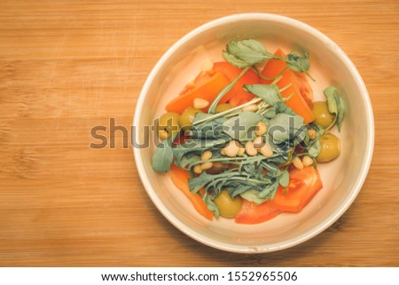 Salad with arugula in a plate on wood
