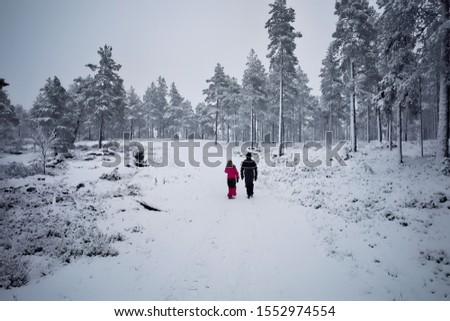 Mother and child walking in a beautiful snowy forest hill.