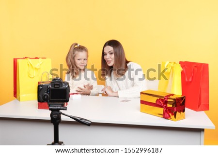 Little girl blogger sitting with mother and recording vlog together.