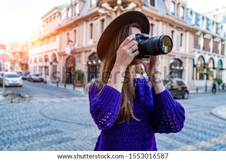 Photographer woman taking pictures with dslr camera and lens during walking around european city