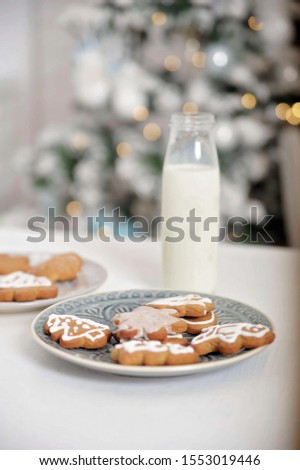 Plate of cookies and glass of milk near Christmas tree