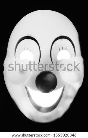 Carnival mask clown backlit on black background. Effect scary, horror.