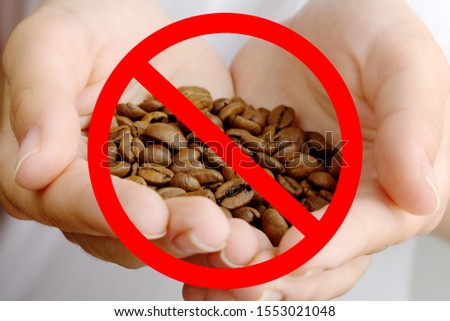 Danger and harm of caffeine. Red prohibitory sign on coffee beans in female hands