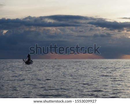 lonely small fishing boats on the open ocean against a background of storm clouds at sunset 