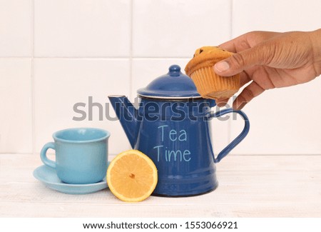 Tea Time Teapot with lemon, cup and saucer on whitewashed wood kitchen counter tile background