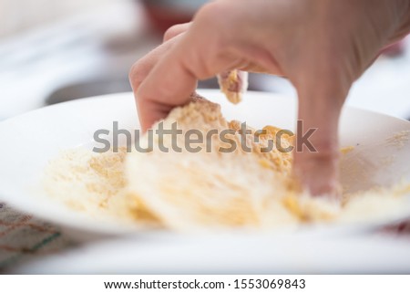 Cropped picture of a hand that stirs mushrooms in a white plate with flour and eggs. Copy space picture