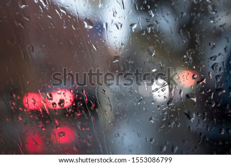 filled frame detailed close up wallpaper shot of drops of rain water on a car windshield window with bokeh blurred city and car lights in the background forming beautiful textures, patterns, shapes 