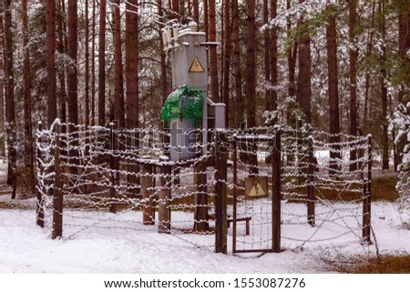 Electrical substation is fenced with barbed wire in the winter.