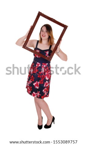 A lovely smiling young woman holding up a picture frame and looking
trough, smiling, isolated for white background
