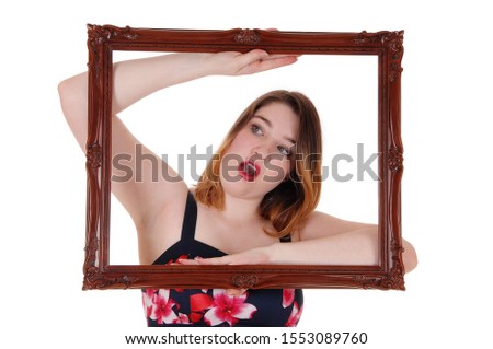 A lovely smiling young woman holding up a picture frame and looking
trough, in close up, isolated for white background
