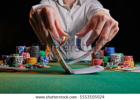 Girl dealer or croupier shuffles poker cards in a casino on the background of a table, chips,. Concept of poker game, game business