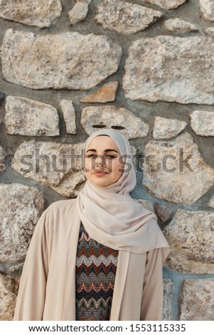 portrait of young European Muslim women with hijab. Stone wall is in her background. She is happy and relaxed.