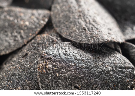 background of many black chips with spices on a slate dish. close-up.