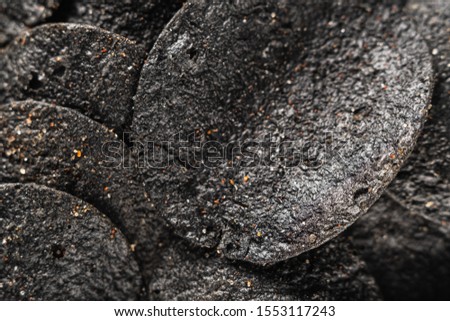 background of many black chips with spices on a slate dish. close-up.
