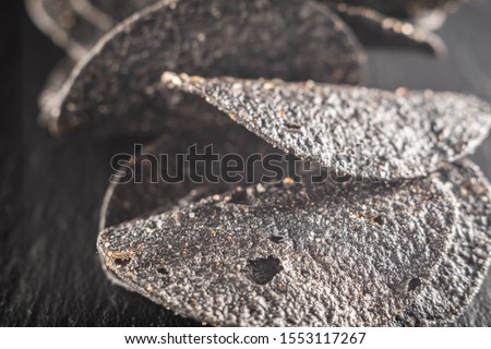 a lot of black chips with spices on a slate dish. close-up.